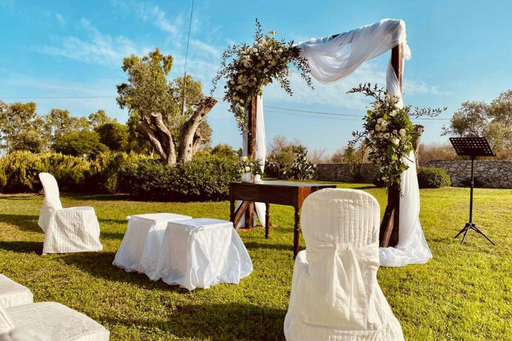 An outdoor wedding setup with white linens and chairs