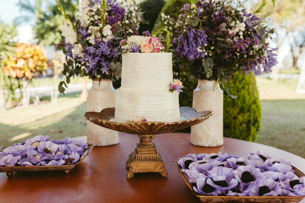 A table topped with a white cake and purple flowers